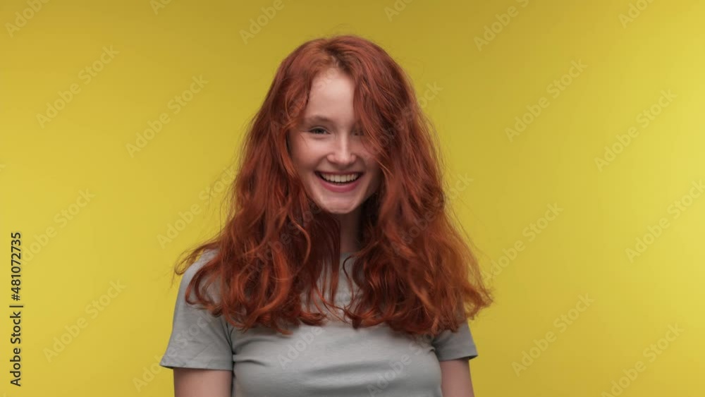 Fancy vivid Caucasian girl curly fly hair in casual t-shirt posing isolated on yellow background in studio. People lifestyle concept. Dancing fooling around have fun gesticulating hands. Fancy vivid Caucasian girl curly fly hair in casual t-shirt posing isolated on yellow background in studio. People lifestyle concept. Dancing fooling around have fun gesticulating hands.