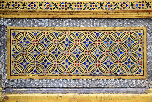 Gold yellow paint patterns with colorful tile fragments decorative on temple wall background of Thai Temple at Thailand.
