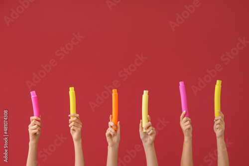 Hands with popular pop tubes on color background