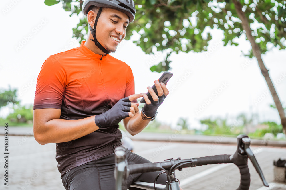 road bike cyclist sitting on his bike while using mobile phone