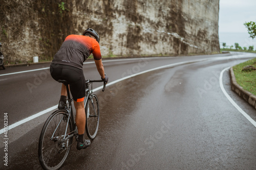 male cyclist riding his bike in country side shoot from the back