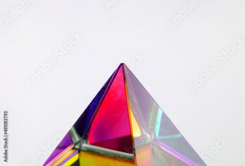 Free Download Tip of color dividing prism. Refraction of light in a color dividing glass prism. Focus is vertex. Shallow depth of field. isolated on neutral white with natural shadows. - GFXLoad