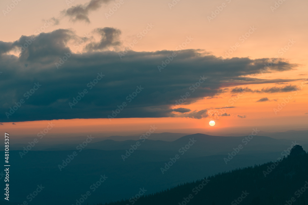 The sun is setting behind the tops of mountains in a summer evening. Dramatic sunset clouds clouds flying over mountain range and forest. View from the top. 4k time-lapse The sun is setting behind the tops of mountains in a summer evening. Dramatic sunset clouds clouds flying over mountain range and forest. View from the top. 4k time-lapse