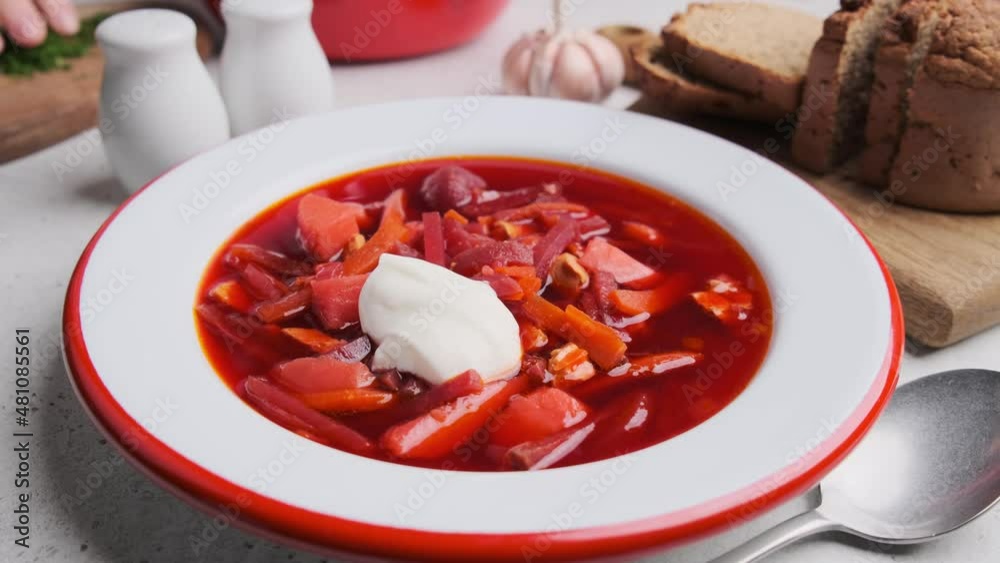 Eating beetroot soup borsch with sour cream, dill and bread with a spoon. Russian or Ukrainian cuisine concept.