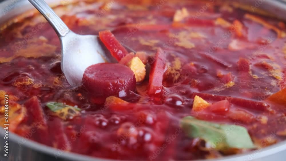 Cooking Russian beetroot soup borsch in red saucepan. 