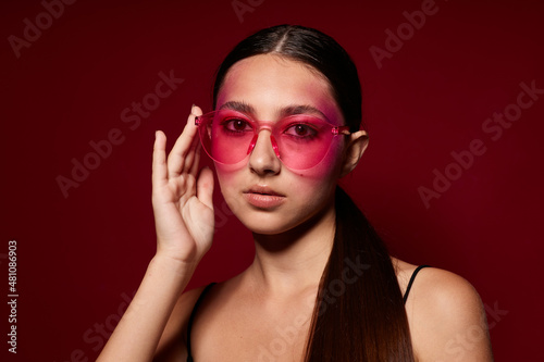 Beauty fashion female pink glasses bright makeup posing black jersey pink background unaltered