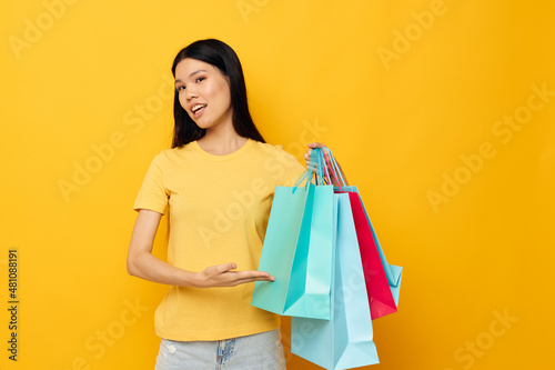 woman in a yellow T-shirt with multicolored shopping bags isolated background unaltered