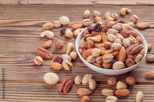 View of mixed nuts on wooden background. Walnut, pistachios, almonds, hazelnuts and cashews. Soft focus.