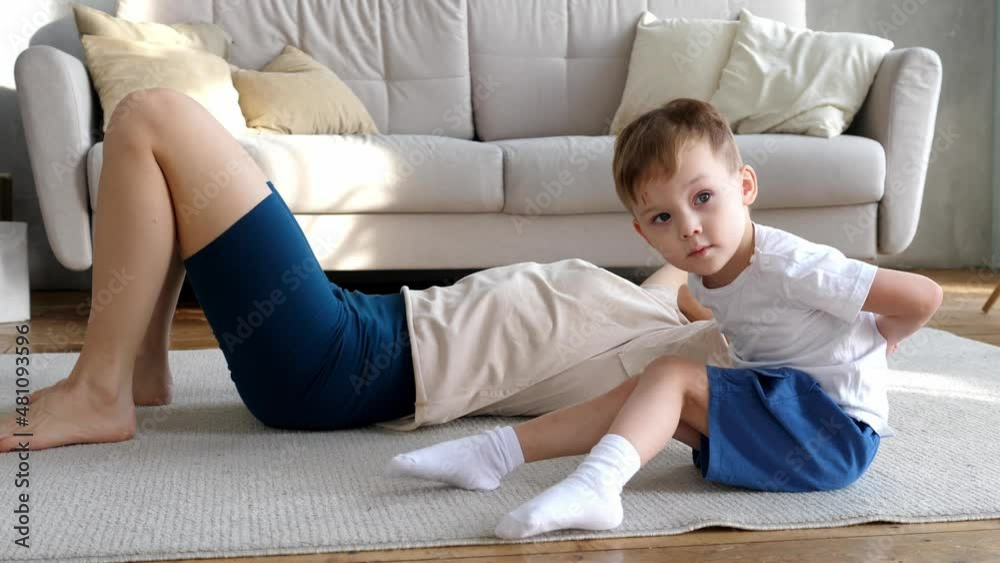 Little boy with his mother goes in for sports at home in the living room. Happy sports family from a young age Little boy with his mother goes in for sports at home in the living room. Happy sports family from a young age