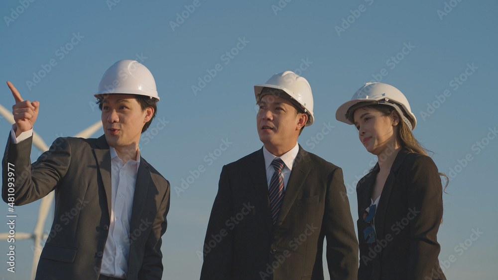 Team of asian businessman and engineers in a black suit talking for future wind turbine installation projects. Teamwork, Brainstorming, renewable energy.