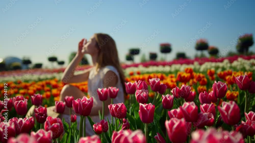 Young woman smiling in bright flower garden. Woman profile in flower background.