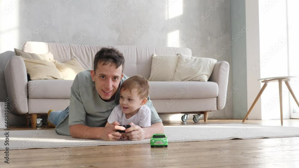 Caring young father plays with his preschool son, drives a radio-controlled toy car, loves to spend time together. Young family having fun playing Caring young father plays with his preschool son, drives a radio-controlled toy car, loves to spend time together. Young family having fun playing