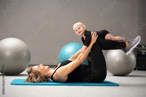 Fitness with a baby.
A woman trains with a child in a fitness room.