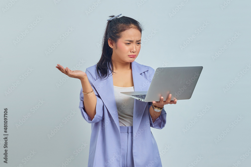 Portrait of sad young Asian woman showing copy space in palms and holding laptop isolated on white background Portrait of sad young Asian woman showing copy space in palms and holding laptop isolated on white background