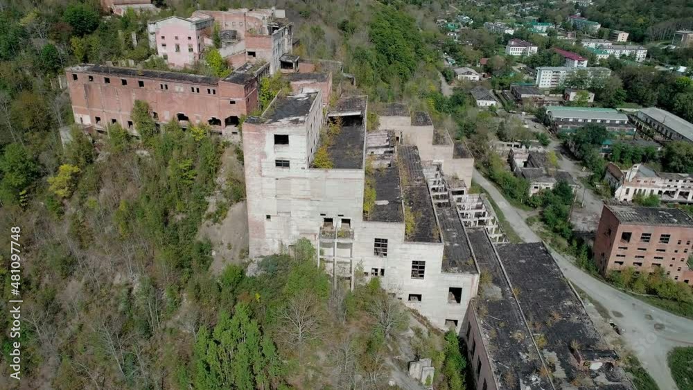 Aerial orbital view of an abandoned factory in natural landscape. Ruined mountain-concentrating combine.