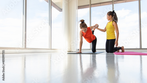 Asian trainer helping woman to do yoga