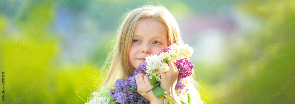 Fototapeta premium Banner with spring kids portrait. Little girl in the garden with long fair hair being excited to get a bouquet of lilac on a birthday.