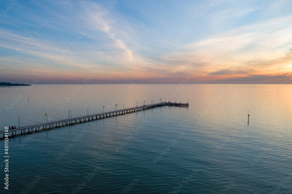 Long wooden pier at sunset - aerial view