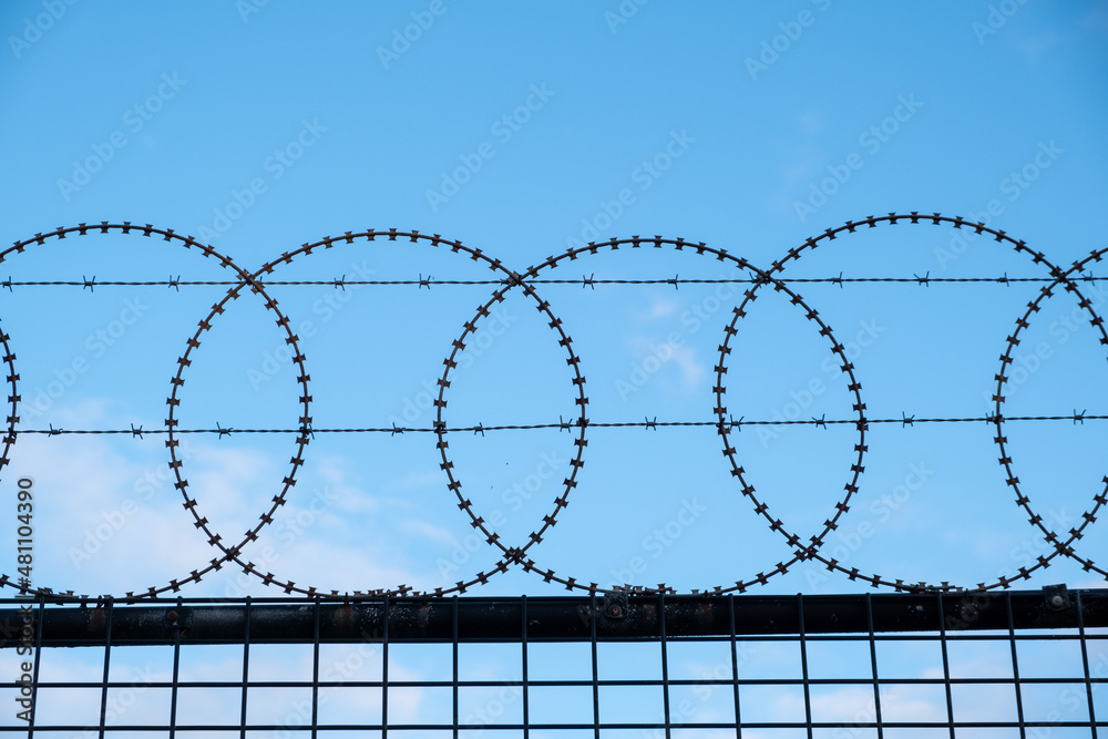 Round barbed wire fence against blue sky with copy space Round barbed wire fence against blue sky with copy space