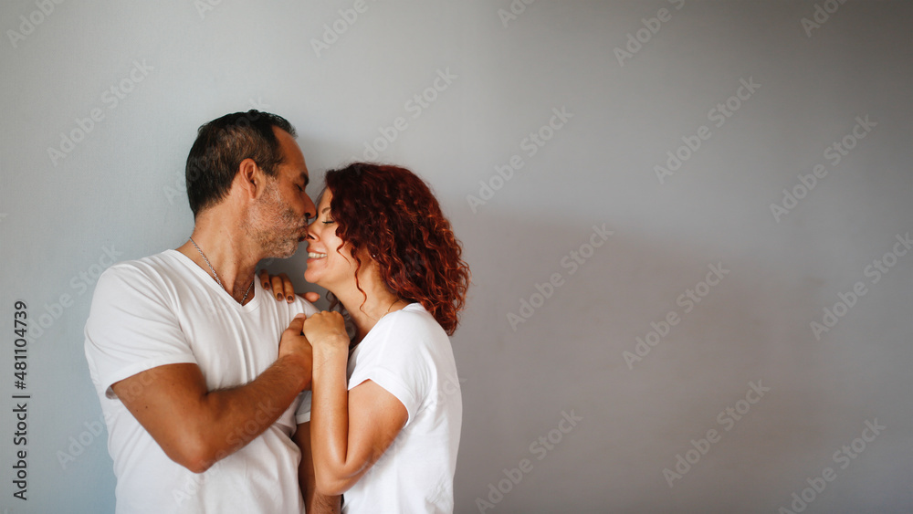 Cute European middle-aged couple tender hugs against a gray wall. Man and woman together, support. gray plain background, copy space Cute European middle-aged couple tender hugs against a gray wall. Man and woman together, support. gray plain background, copy space