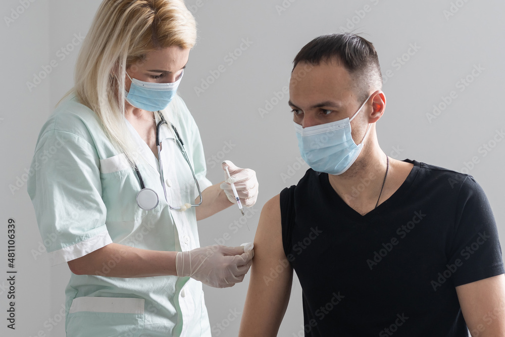 COVID-19 vaccine injection, doctor in gloves holds syringe and makes jab to woman patient in clinic. Prevention of coronavirus or influenza. corona virus and flu shot, therapy and treatment. - obrazy, fototapety, plakaty 
