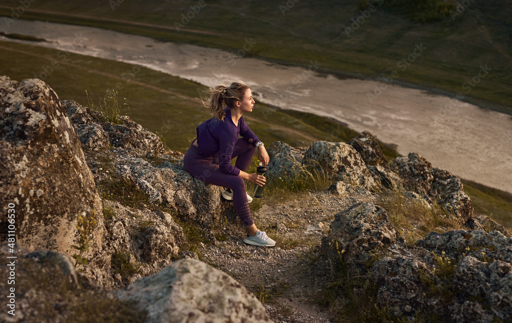 Sportswoman taking break and drinking water during training