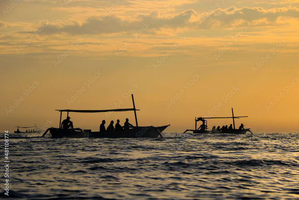 silhouette of fishing boat crossing the sea at sunset