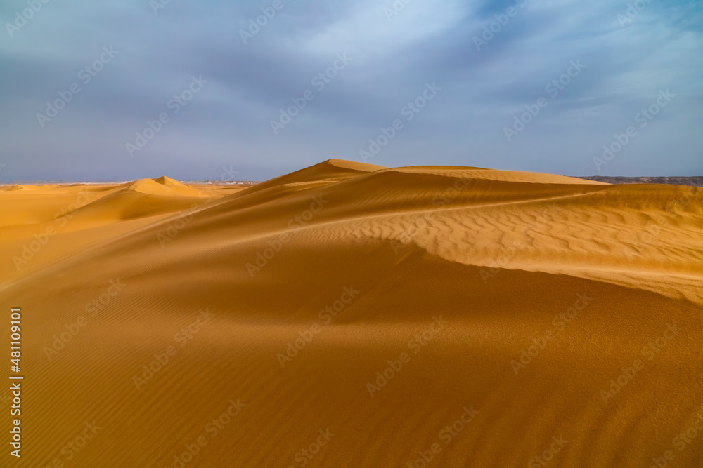 Strong wind at sunset over the sand dunes in the desert. Sandstorm in the Desert