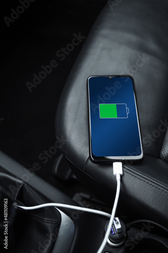 Mobile phone ,smartphone, cellphone is charged ,charge battery with usb charger in the inside of car. modern black car interior photo