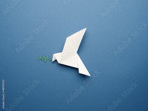Canvas White origami pigeon on a blue paper background, peace or freedom concept