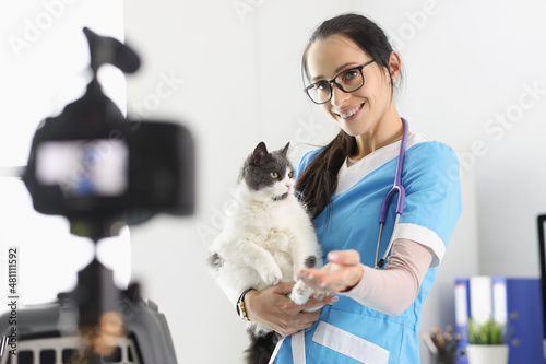 Fototapeta Naklejka Na Ścianę i Meble -  Female doctor present cute kitty on camera, petting him for video