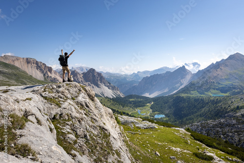 Hiker with raised arms next to a scenic mountain landscape