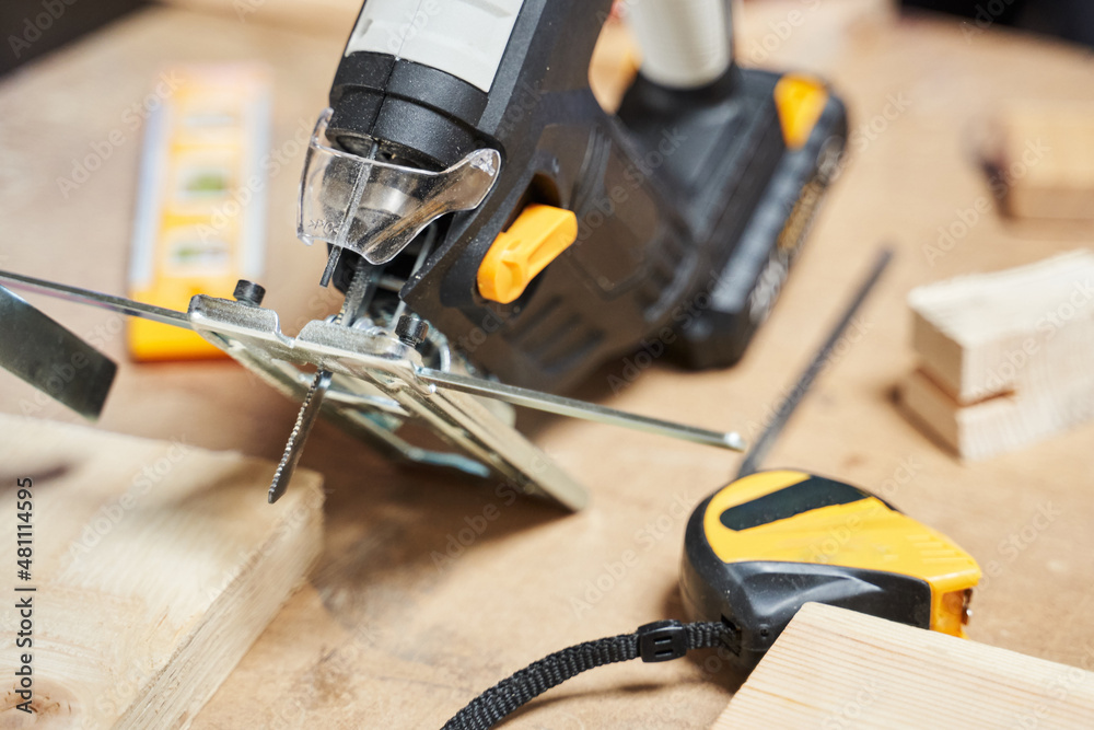 jigsaw with battery with a limiter on a workbench, next to other tools jigsaw with battery with a limiter on a workbench, next to other tools