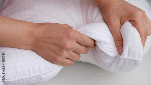 Young woman touching soft white pillow, closeup. how to choose a pillow, artificial filling © yavdat