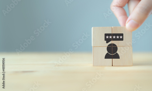 Consumer feedback concept. Customer satisfaction evaluation to improve and develop product and service. Customer centric. Hand puts wooden cubes with "feedback" icon on grey background ,copy space.