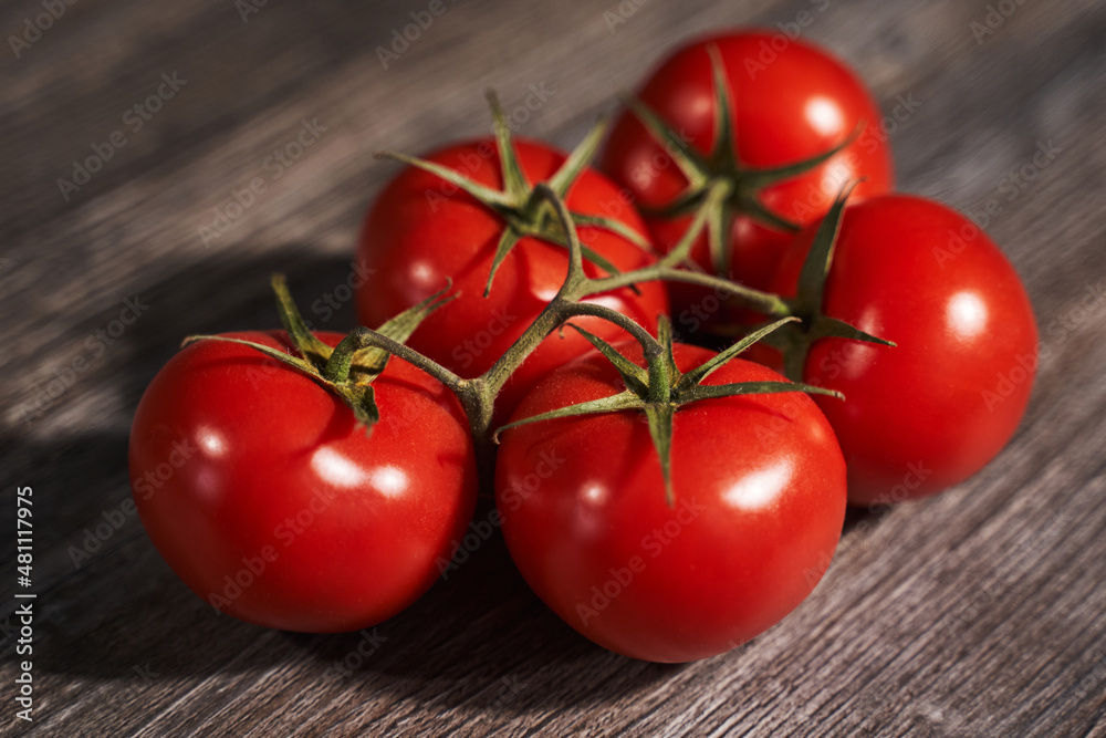 red ripe tomatoes on a branch on a wooden background red ripe tomatoes on a branch on a wooden background