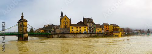 Panoramic view of Seyssel embankment on Rhone river with ancient Saint-Blaise church and suspension bridge on winter day, Haute-Savoie department, France