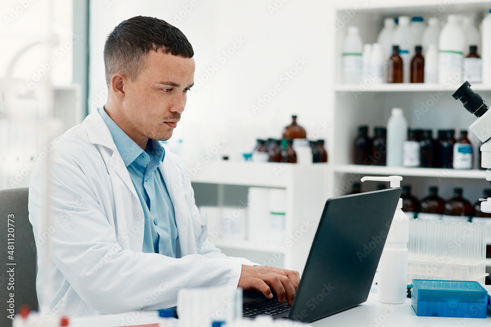 Keep calm, the cure is coming. Shot of a young scientist using a laptop while working in a laboratory.