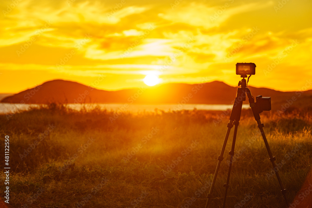 Naklejka premium Camera taking picture of sunset over sea