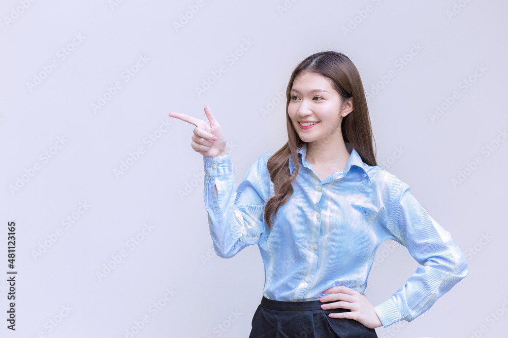 Asian business working woman with long hair who wear a blue long sleeve shirt smiles happily while she shows point up to present something on white background. Asian business working woman with long hair who wear a blue long sleeve shirt smiles happily while she shows point up to present something on white background.