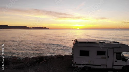 Aerial view. Flying above camper rv camping on coast sea shore at sunrise. Adventure, travel with mobile home.