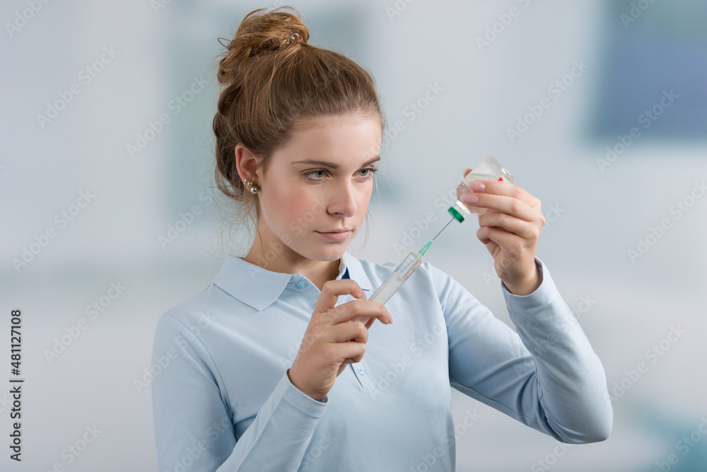 young female doctor's assistant or nurse pulls up a syringe in front of a clinic room young female doctor's assistant or nurse pulls up a syringe in front of a clinic room