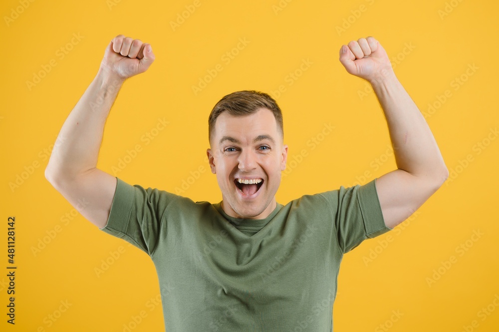 Excited young man guy posing isolated on yellow background studio portrait. People lifestyle concept. Mock up copy space. Rising hands, clenching fists like winner Excited young man guy posing isolated on yellow background studio portrait. People lifestyle concept. Mock up copy space. Rising hands, clenching fists like winner