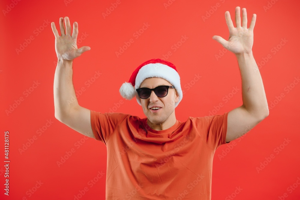 Naklejka premium concept people, body language, approval, recommendationan excited man Santa Claus hat isolated on red studio background with space for text