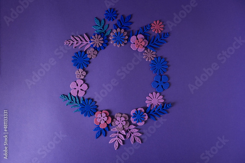 Round frame with handmade flowers on a purple background Cut from paper. photo