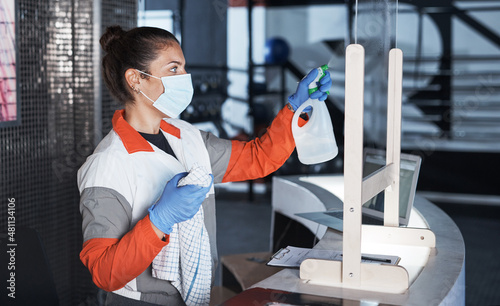 She routinely keeps the space clean. Shot of a young woman cleaning the reception desk in a gym. photo