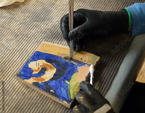 Foto Cleaning old tiles with a scalpel and cotton swab