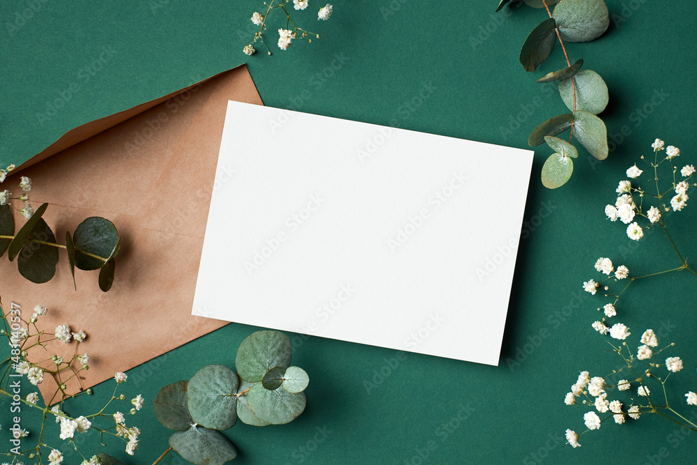© nikavera - Invitation or greeting card mockup with envelope, eucalyptus and gypsophila flowers on paper background
