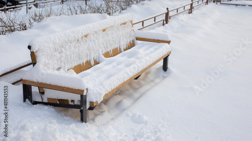 Snow-covered bench sunk in the snow, a large amount of precipitation in winter