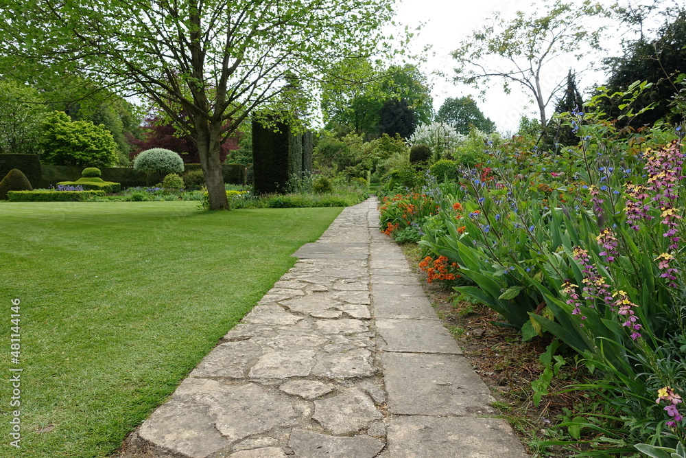 Scenic view of a path through a beautiful landscape garden with colourful flowers and grass lawn